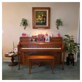 Kranich & Bach upright piano with matching bench, surrounded by porcelain figurines and framed flora