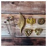 Vintage brooches and stickpins with floral, leaf and decorative designs.