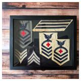 Vintage U.S. Navy rating patches and service stripes presented together in a framed display.
