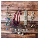 Vintage costume jewelry assortment featuring colorful necklaces, rhinestone bracelets and brooches.