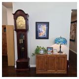Traditional wooden grandfather clock with pendulum and decorative dial.