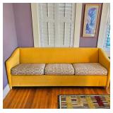 MCM style sofa, mustard yellow, with swooping, angled arms.