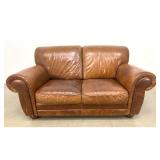 Lot 1215  Contemporary Club Style 2 Seat Loveseat in Distressed Cognac Leather with Rolled Arms and Bun Feet